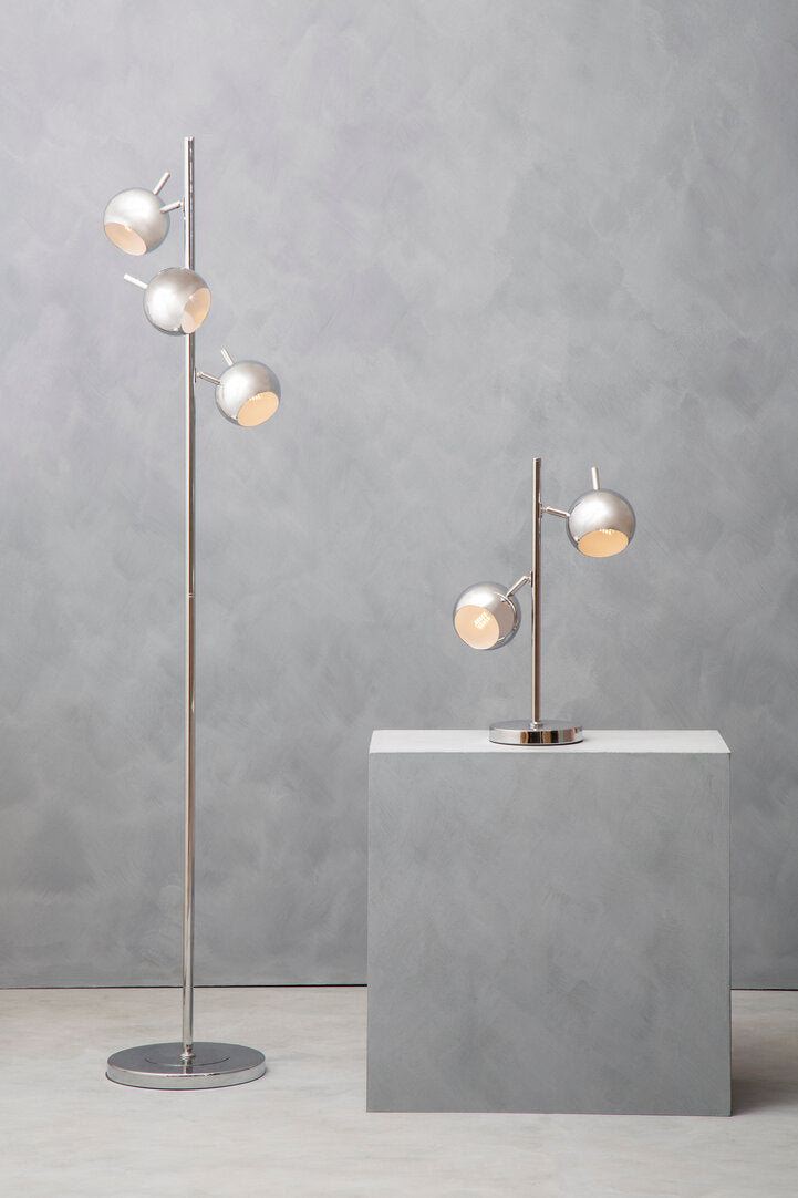 Modern floor lamp and table lamp on a gray pedestal against a gray wall.