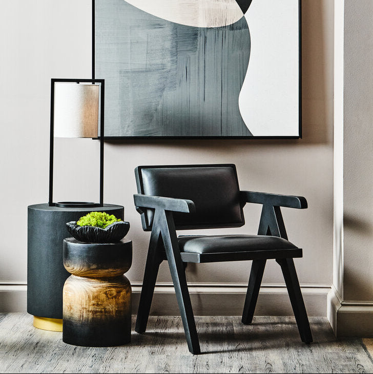 Modern interior with abstract art, black chair, and decorative plants.