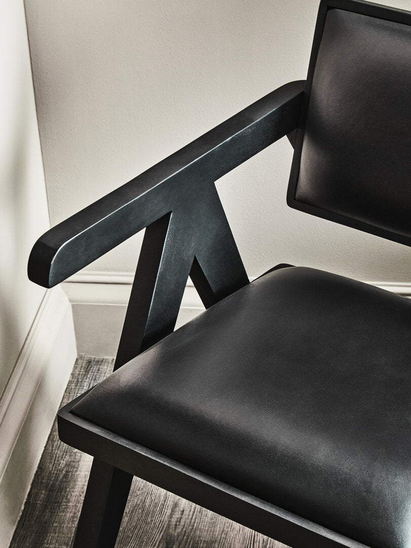 Black leather chair with armrests in a corner