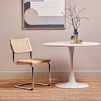 Cesca-like Cantilever Rattan Dining Chair next to round table with vases