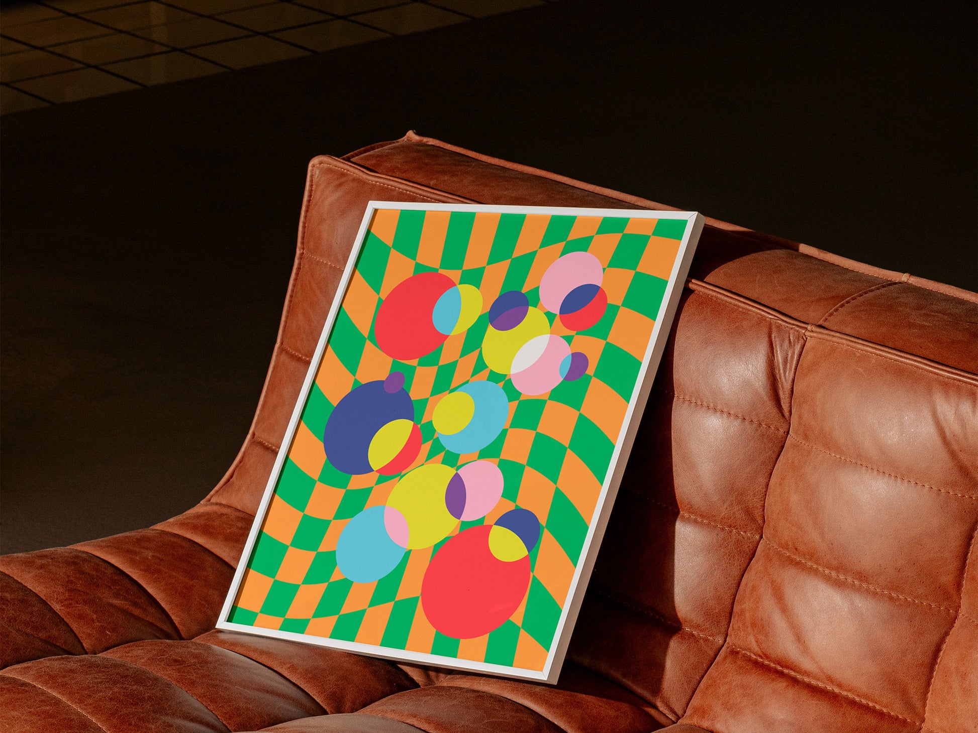 Checkerboard Bubbles Poster in white frame on leather couch