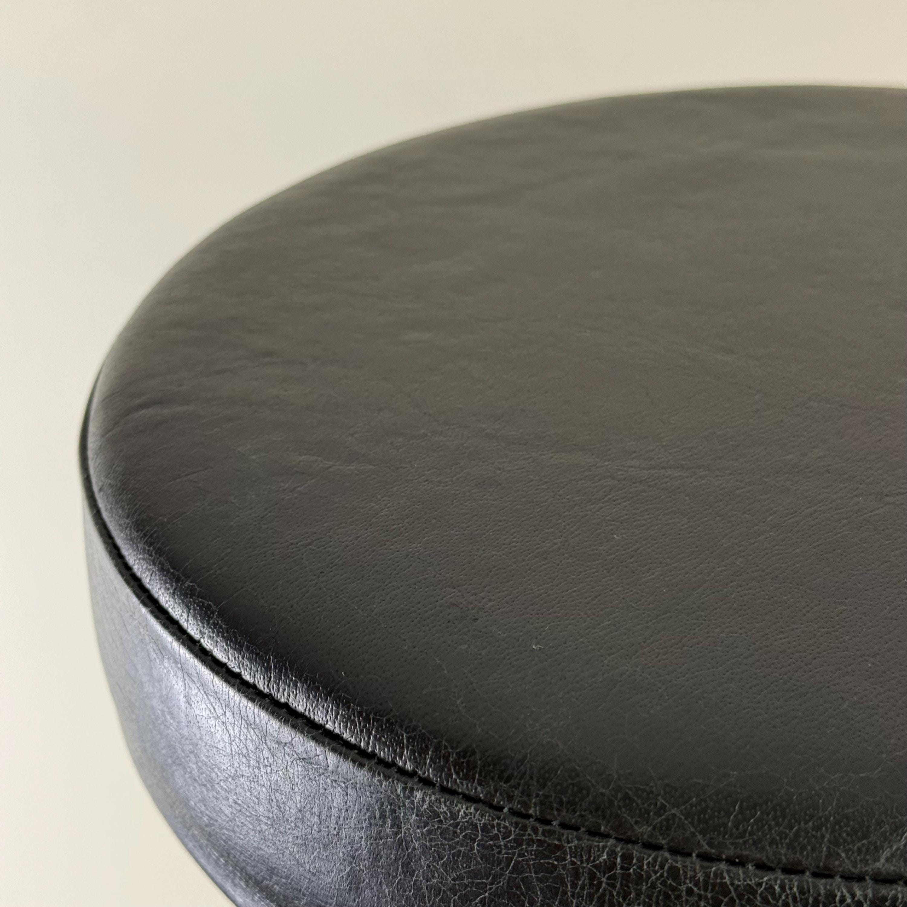 Close-up of a black leather seat cover on a beige background