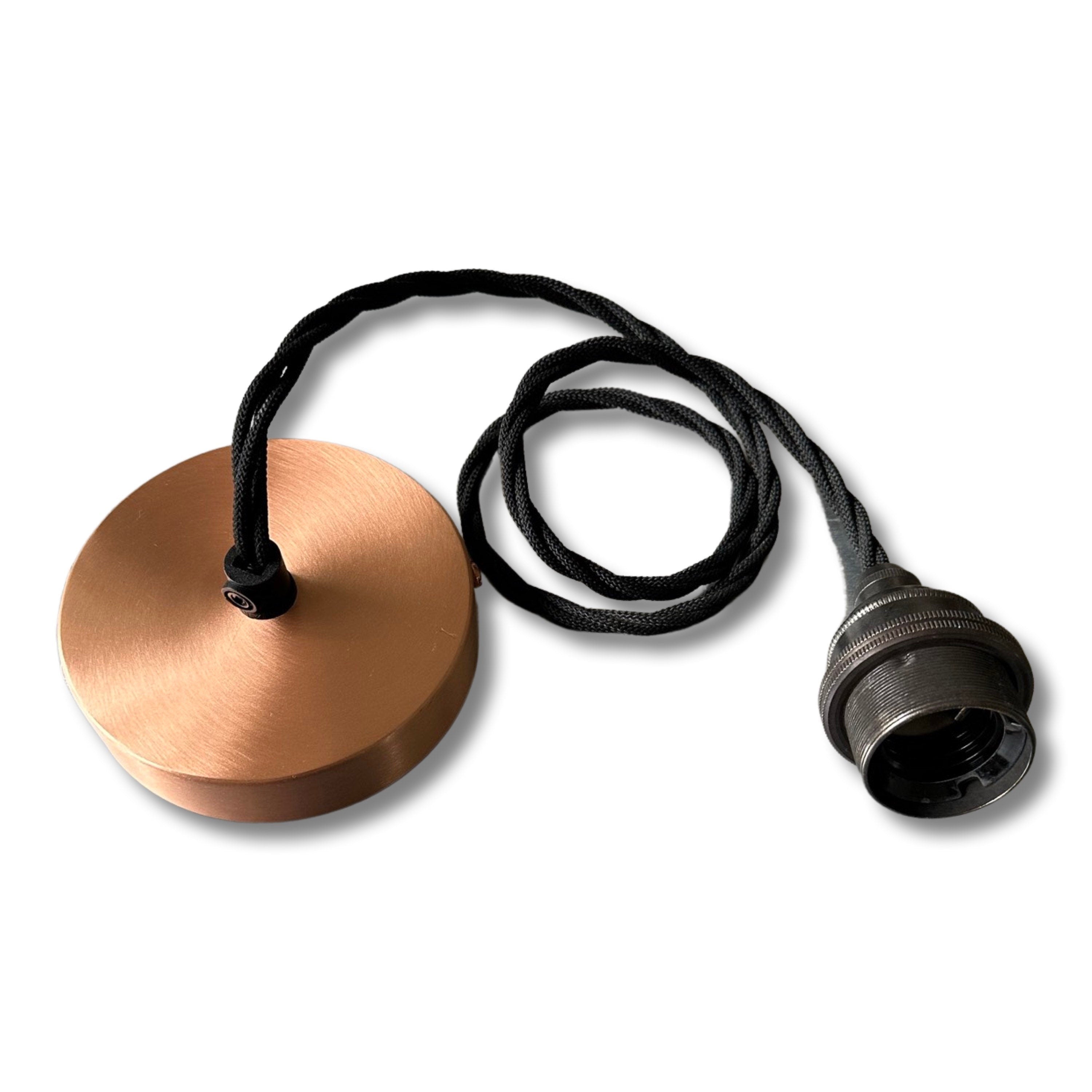 Copper-colored pendant light with black cord on a white background