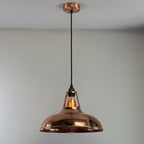Copper pendant light hanging against a plain background