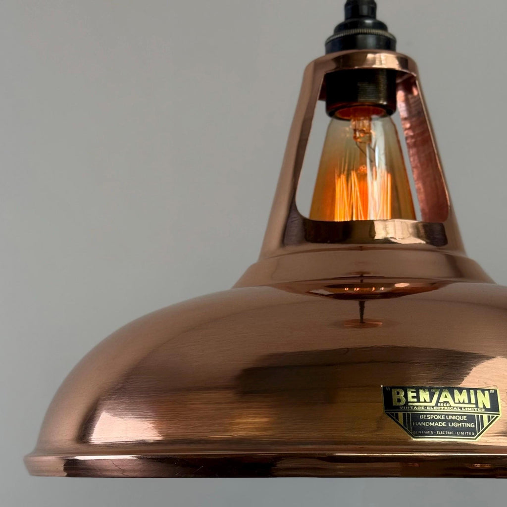 Copper pendant light with a visible brand label on a gray background