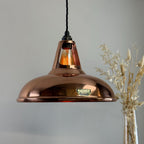 Copper pendant light with a visible brand logo on a gray background