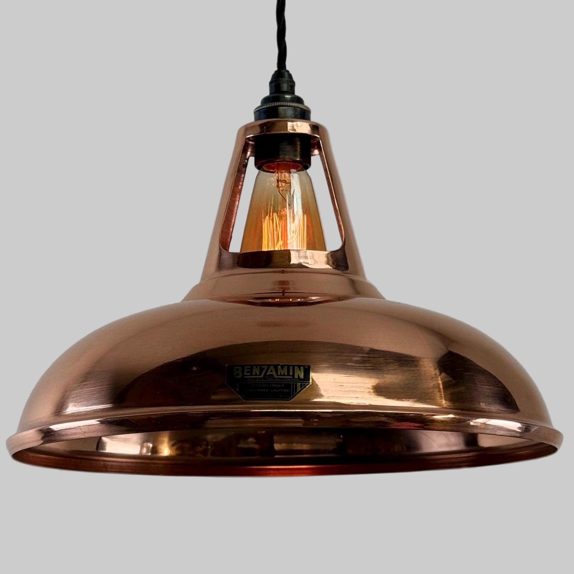 Copper pendant light with a visible brand name against a plain background