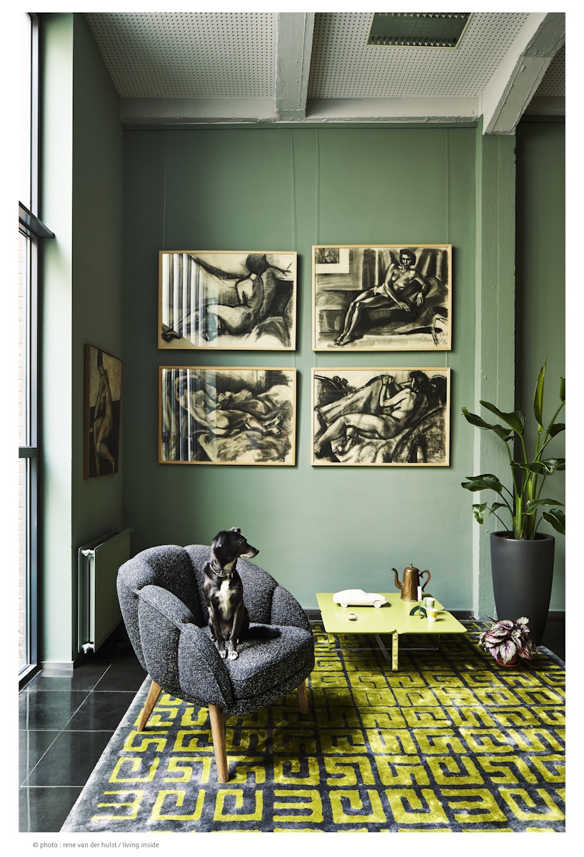 Living room with green walls, gray armchair, yellow coffee table, and decorative elements.