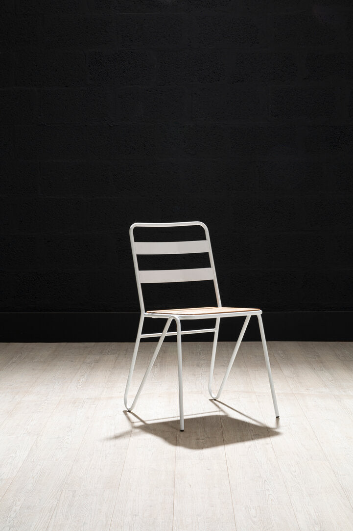 White metal chair against a black wall on a wooden floor