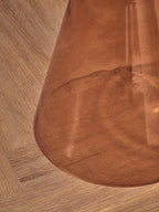 Close-up of a orange glass surface with a visible grain pattern on a wooden floor.