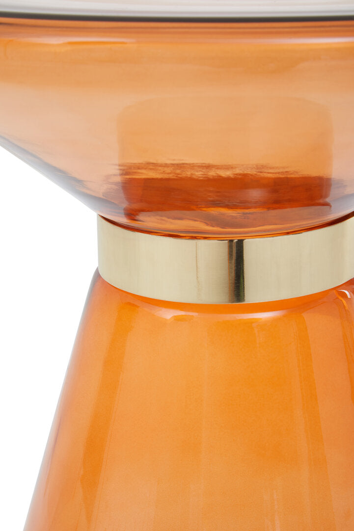 Close-up of an orange glass table with a gold base on a white background