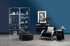 Modern living room with black furniture, a glass shelf, and decorative items against a blue wall.