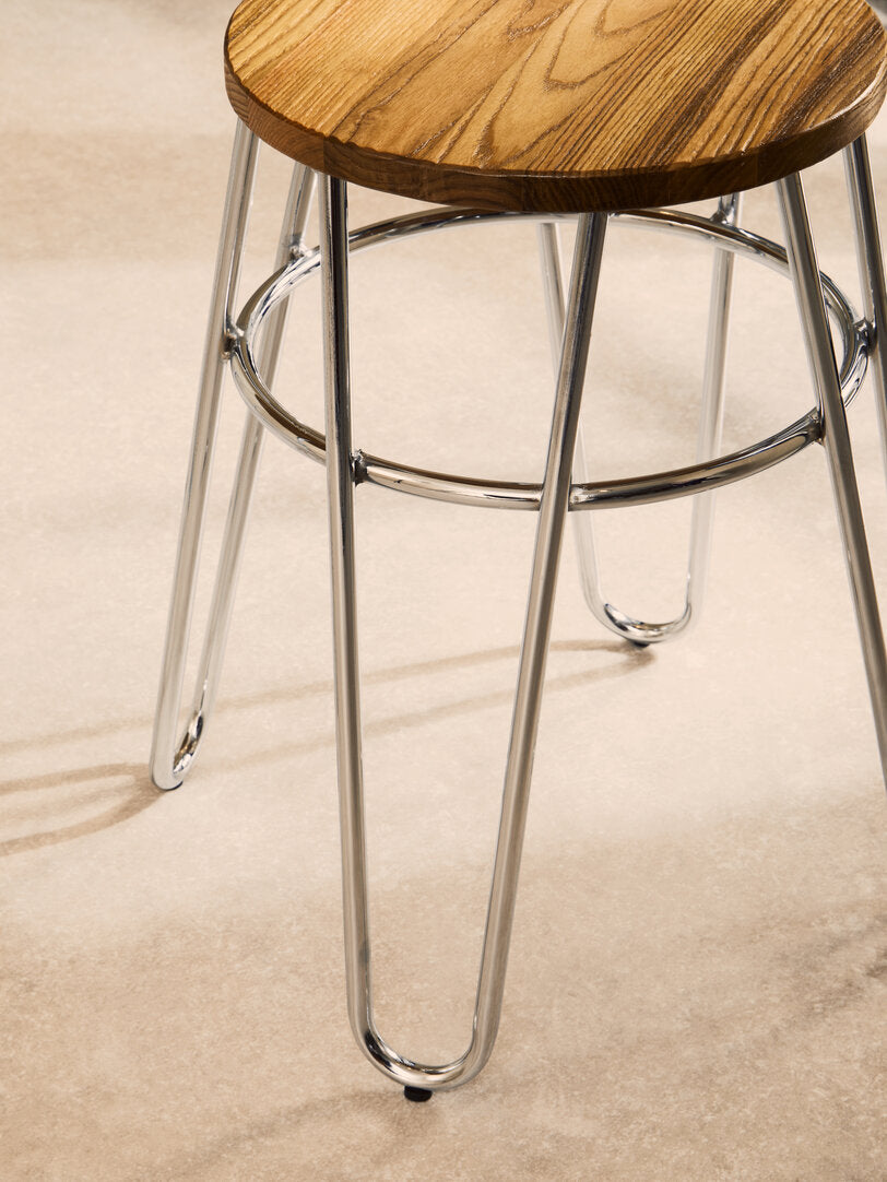 Wooden stool with metal legs on a beige carpet