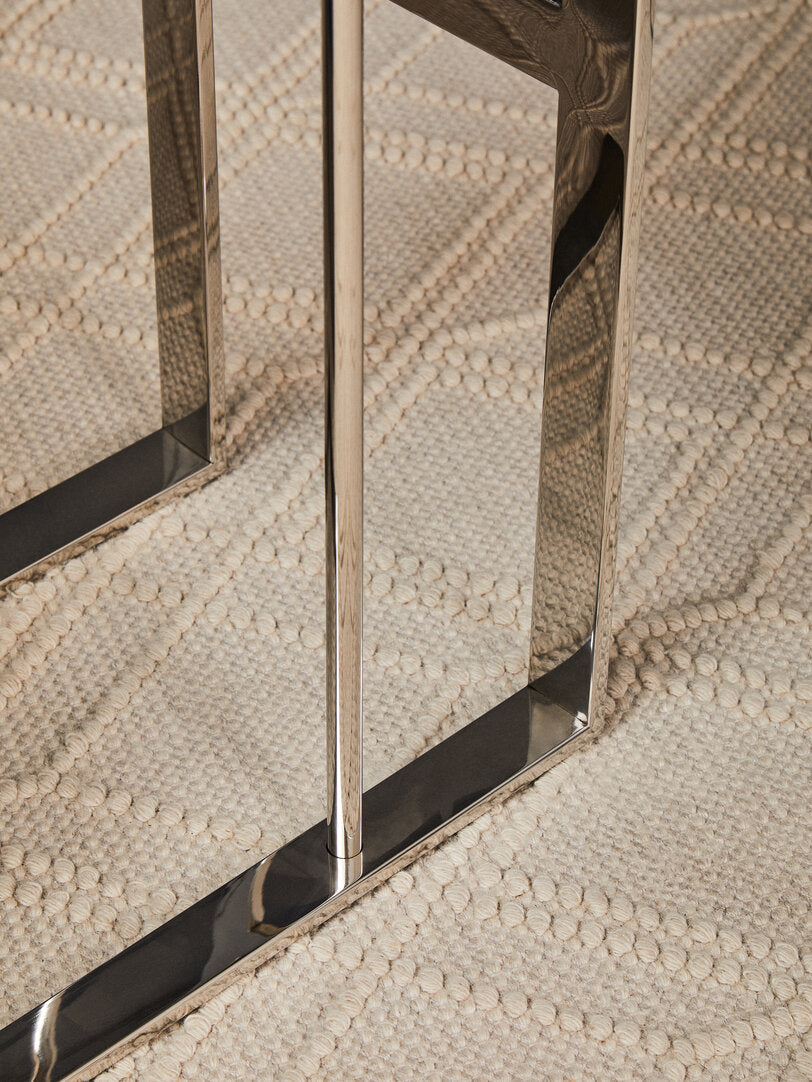 Close-up of a metallic table legs with on a textured rug