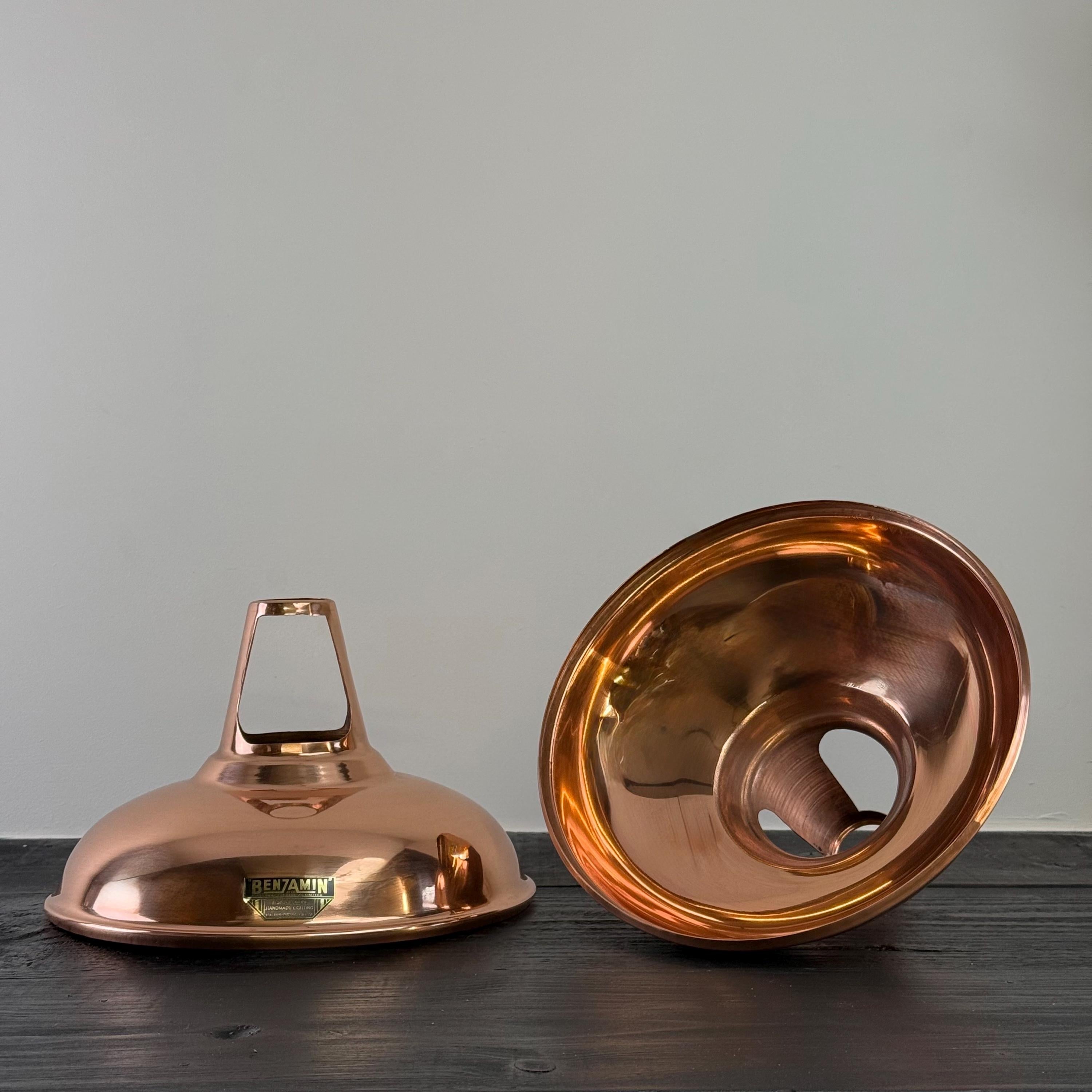 Two copper lamp shades on a wooden surface with a gray background