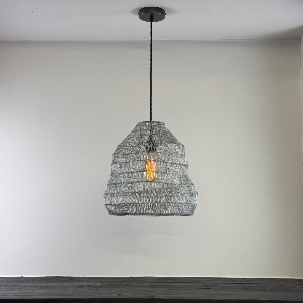 Wire pendant light hanging against a plain wall
