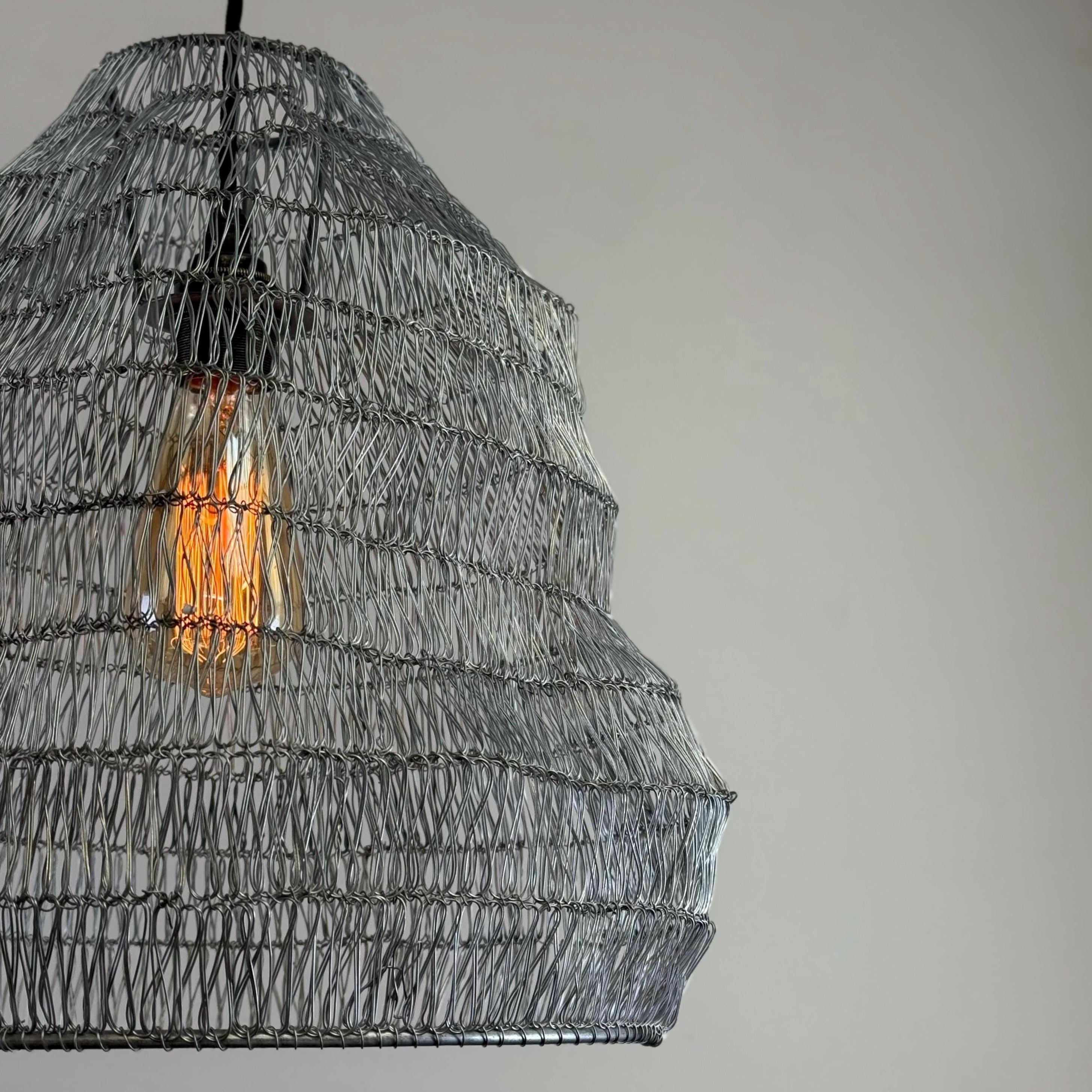 Woven pendant light with a visible bulb against a neutral background