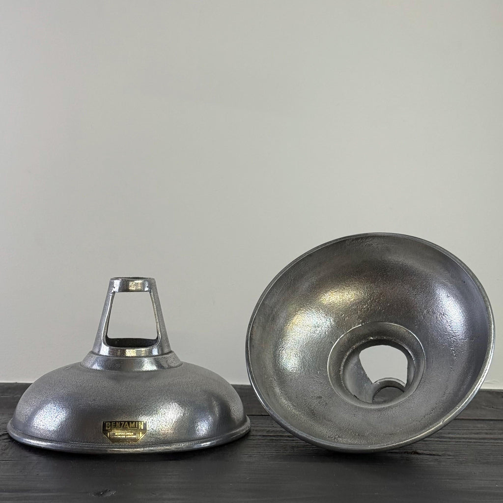 Two metallic lampshades on a wooden surface with a plain background