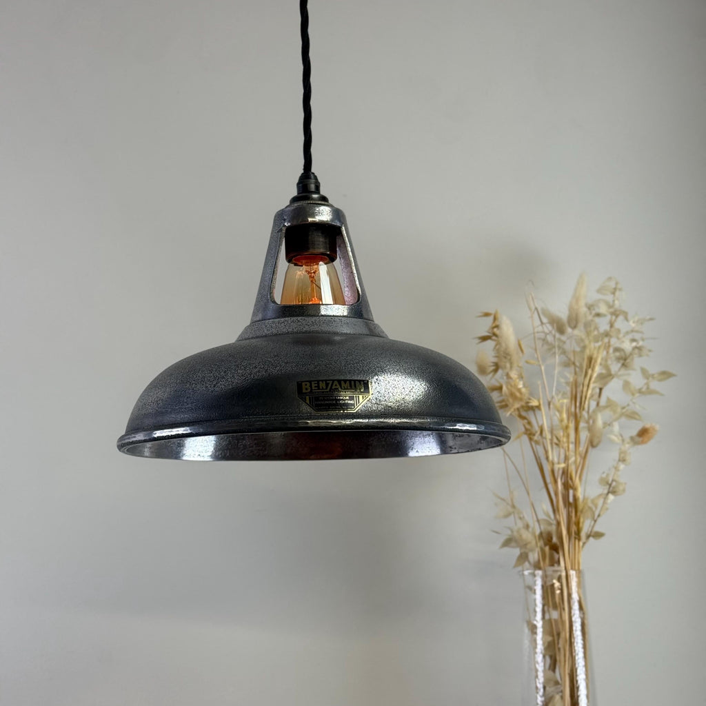 Industrial-style pendant light with a brand logo on a neutral background