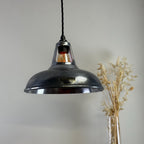 Industrial-style pendant light with a brand logo on a neutral background