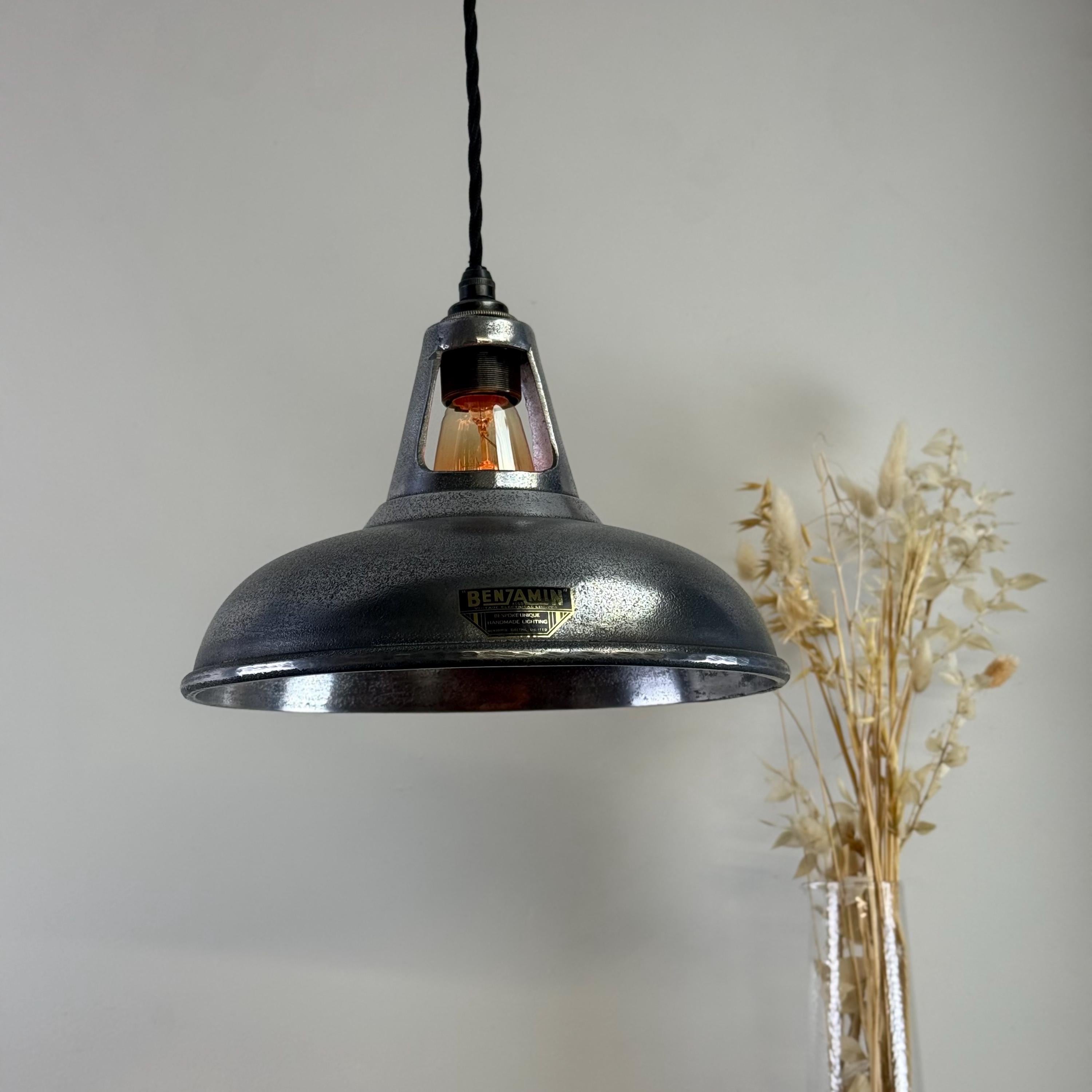 Industrial-style pendant light with a brand logo on a neutral background
