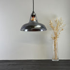 Vintage-style pendant light hanging above a wooden surface with a vase of dried plants.